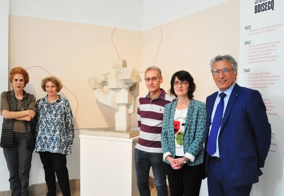 Des hommes et des femmes posent devant une sculpture