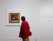 Une femme observe un tableau. 